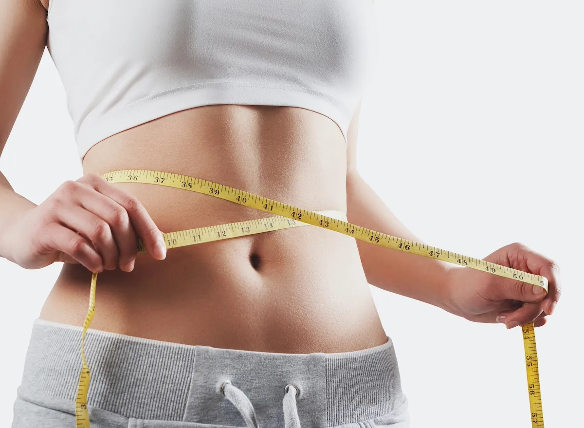 Woman measuring her waist with a tape measure